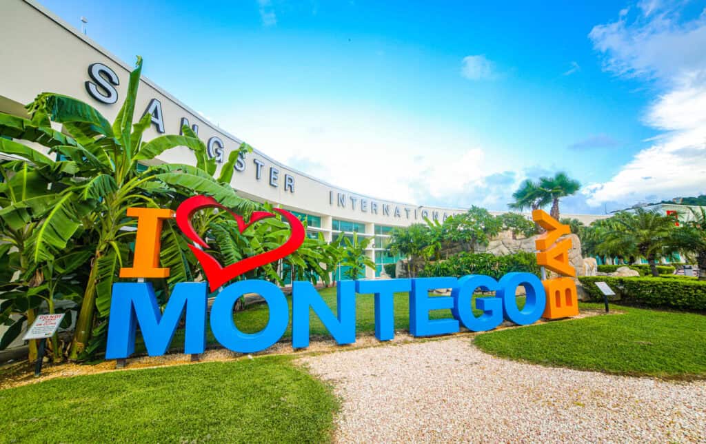 I ♥ Montego Bay" sign at Sangster International Airport with palm trees, gateway to Negril Jamaica.
