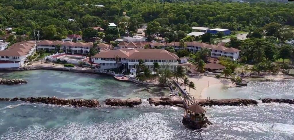 Club Ambiance resort in St. Ann Jamaica with palm trees, turquoise water, and lush greenery seen from above.