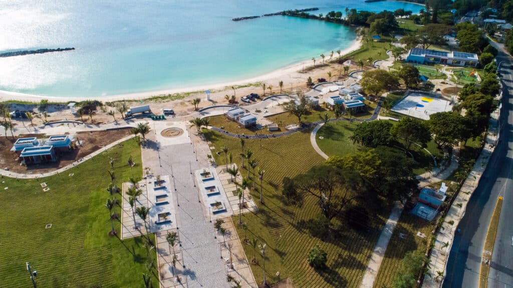Aerial view of Harmony beach park with walking paths, green lawns, palm trees, and turquoise shoreline.
