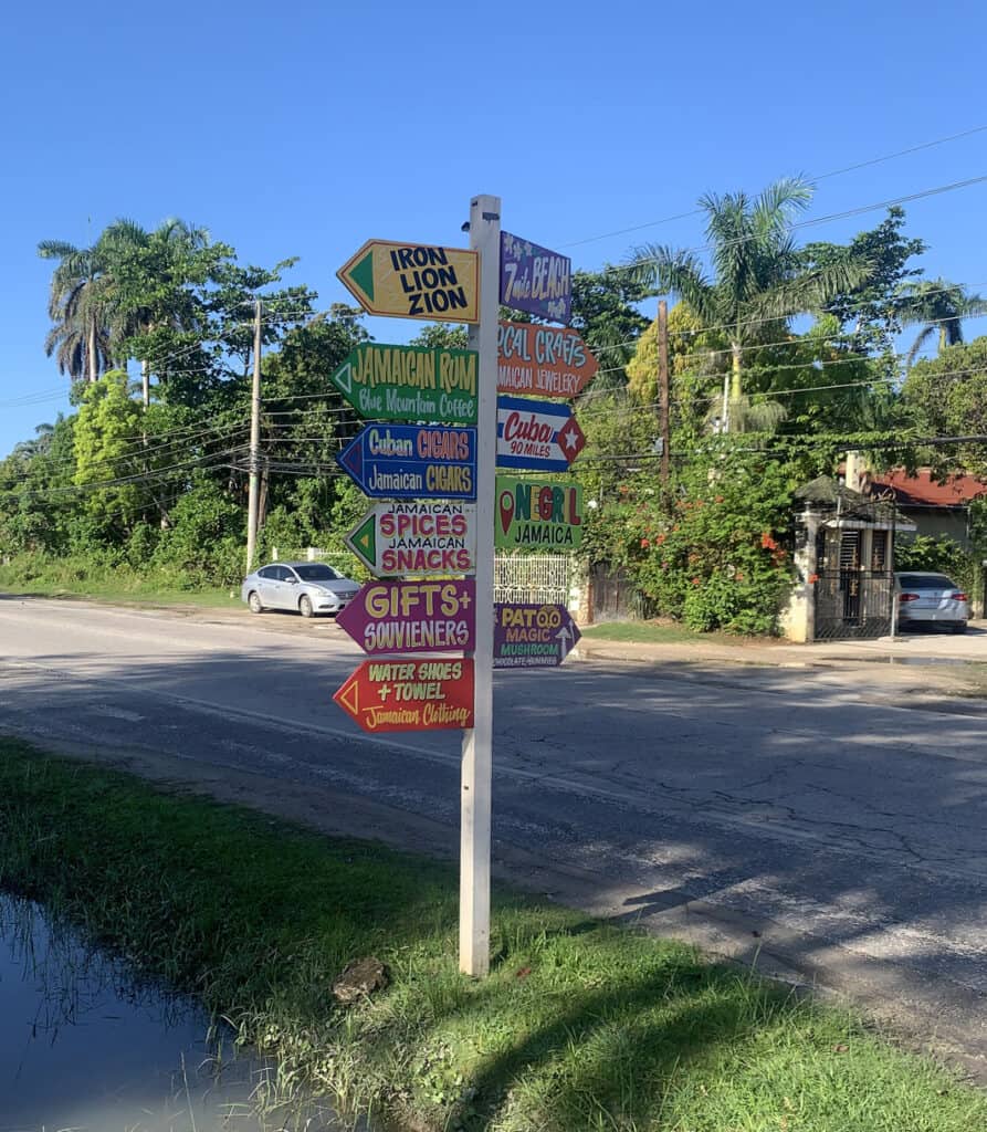 Colorful signpost in Negril Jamaica points to local attractions and businesses along the roadside.