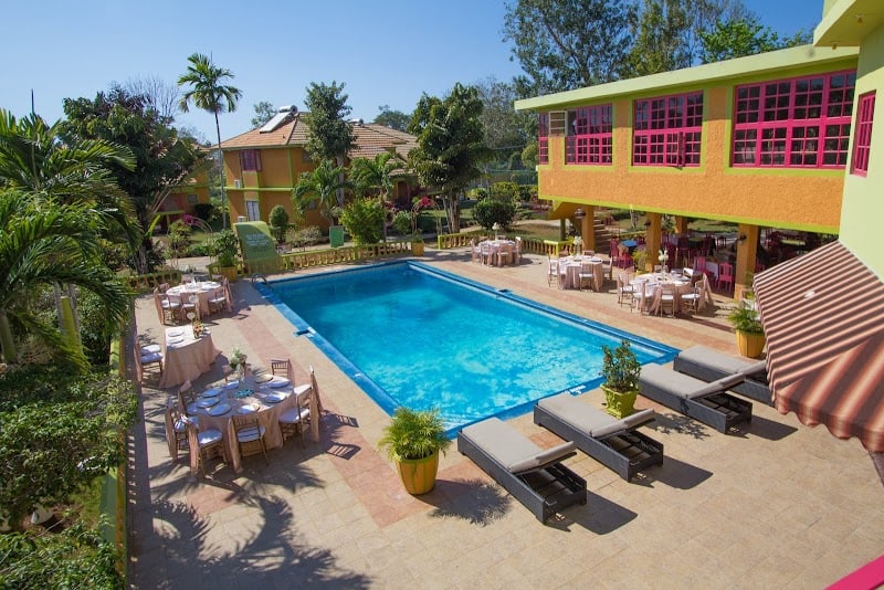 Negril Jamaica pool area with tables, chairs, vibrant buildings, and palm trees in the background.
