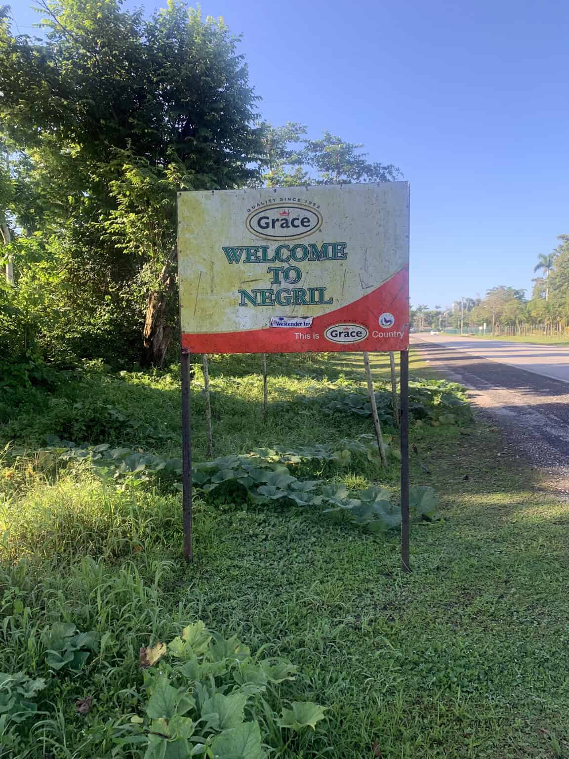 Welcome to Negril sign by Grace along a roadside with lush greenery and trees in Negril, Jamaica.