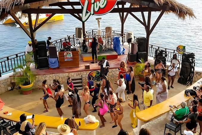 Beachside stage in Negril Jamaica with people dancing and enjoying live music by the water at a vibrant local venue.